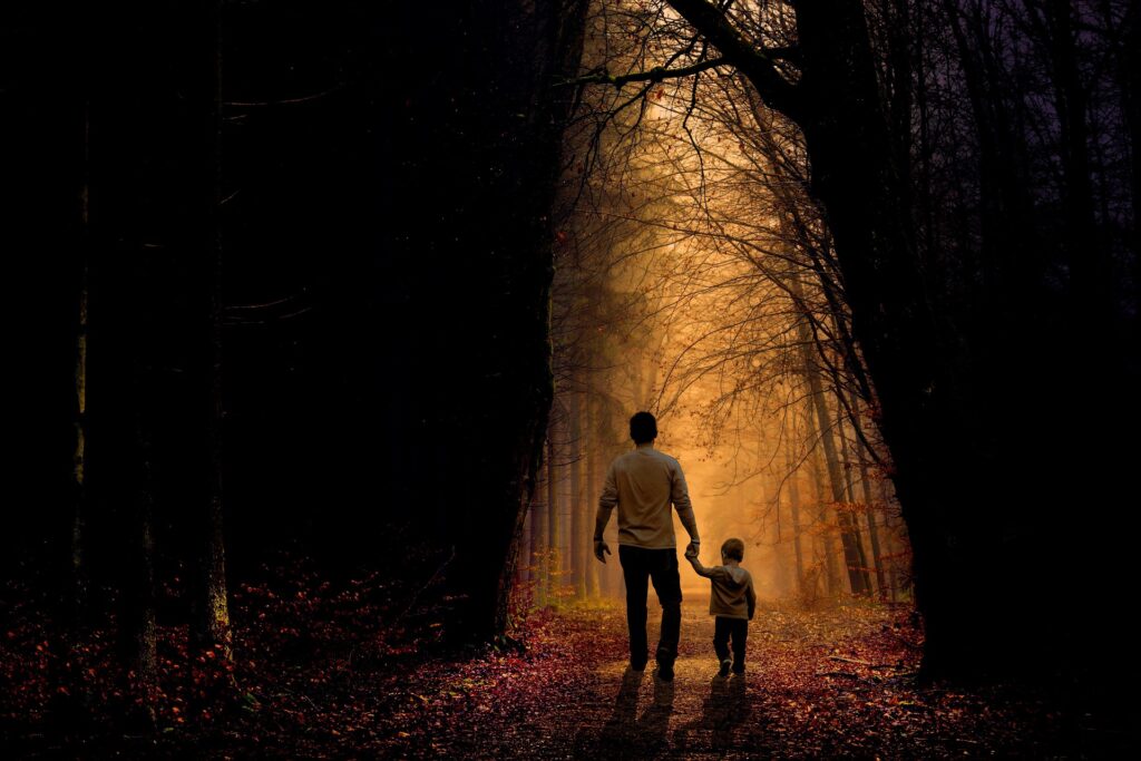 Ein Vater und sein Kind gehen im Wald ins Licht ihrer gemeinsamen Zukunft.